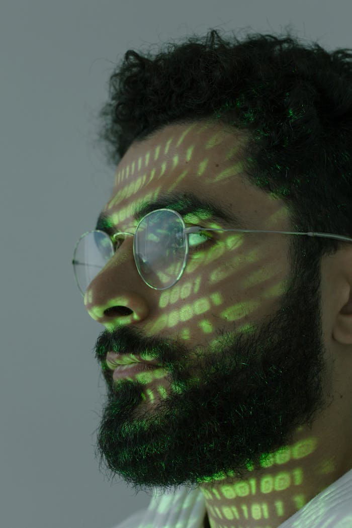 who-we-are Headshot of a man with green binary code projected on face, symbolizing cybersecurity.